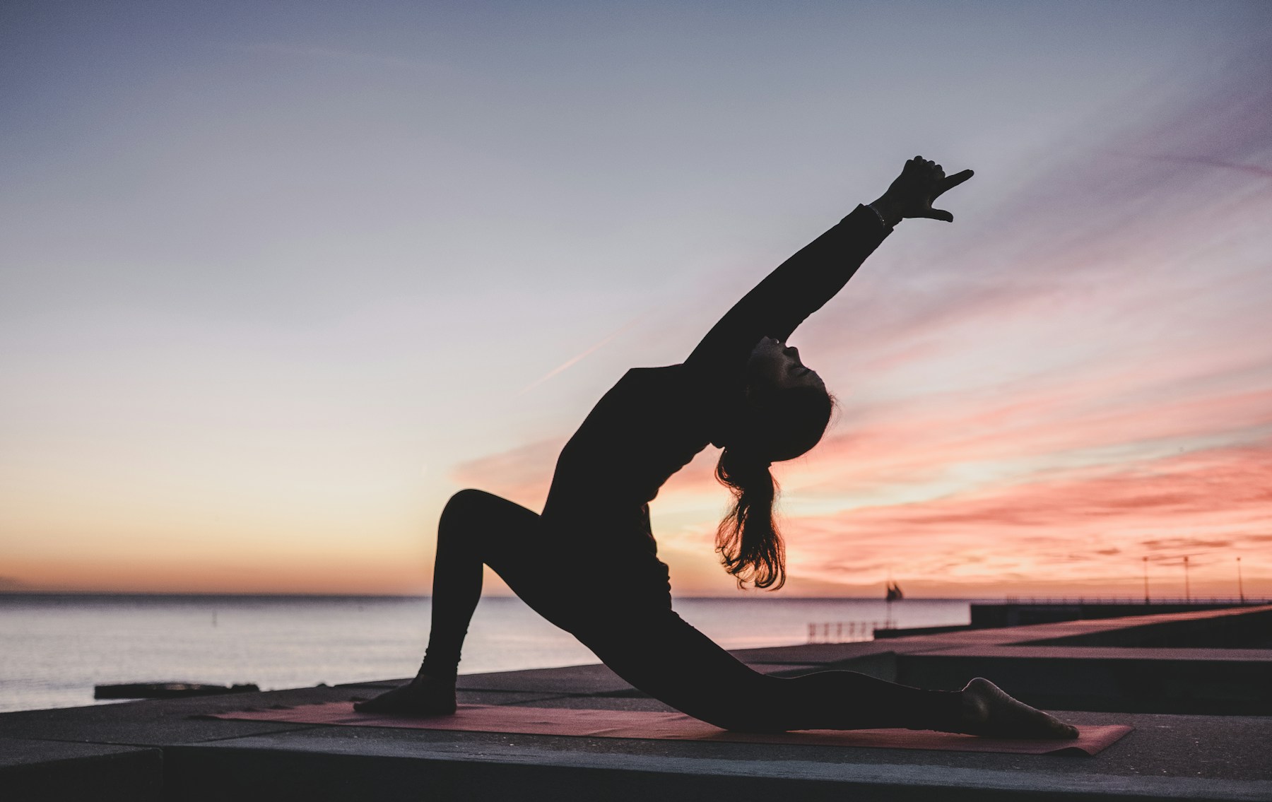 Práctica de yoga frente al mar al atardecer. Fotografía de ilustración.